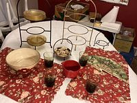 Full view of all items on a red floral tablecloth including plate stands, salad bowl, glasses, fan, and red pitcher