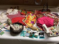 Wide view of sewing lot showing fabric scraps, threads, packages of notions and tools.