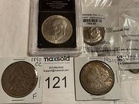 Overview of all five coins: two Morgan dollars in 2×2 holders, slabbed Eisenhower dollar, sealed Kennedy half-dollar, nickel set pouch