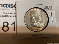Obverse side of 1963 D Ben Franklin half dollar coin in cardboard holder with handwritten '1963 D' marking