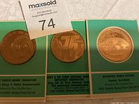 Photo showing all three bronze proof coins in their original packaging with descriptive labels.