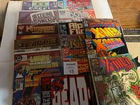 Photo showing multiple comic books stacked and laid out together on wooden table including titles from Marvel and other publishers.