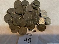 Pile of 62 nickels showing obverse and reverse sides including buffalo and Jefferson designs, some coins stacked.