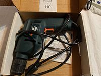 Black & Decker corded drill inside box with power cord and instruction manual underneath