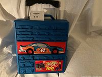 Photo of the blue Hot Wheels plastic carry case with molded car slots and decals featuring race car with number 44 and Hot Wheels branding on front.