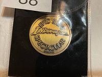 Front of medallion showing 'EPIC STUNT INDIANA JONES SPECTACULAR' text embossed on bronze-colored metal.