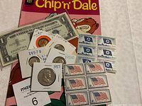 Image showing 1957 US coins, silver certificate one dollar bill, postage stamps and Chip 'n' Dale comic book.