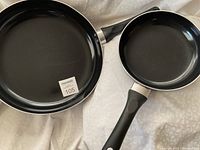 Two black Healthy Living frying pans placed side by side showing the cooking surfaces and black soft grip handles, slight signs of use on the surfaces.