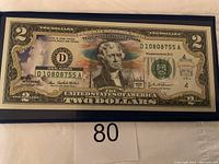 Colorized $2 U.S. bank note featuring Yellowstone National Park in a frame with serial number visible.