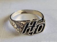 Close-up of the silver Harley Davidson H-D ring showcasing the black enamel H-D lettering and detailed textured sides.