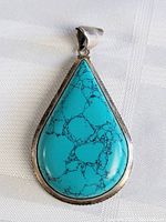 Front view of large teardrop turquoise pendant showing vibrant blue stone and silver setting.