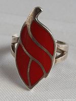 Close-up front angle photo of the sterling silver ring showing the red enamel flame design and split band.