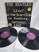 Photo showing front cover of album with text The Beatles Live! at the Star-Club in Hamburg, Germany; 1962, and two vinyl records with purple labels.
