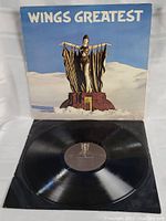 Vinyl record Wings Greatest Hits with cover open, showing the record and cover image.