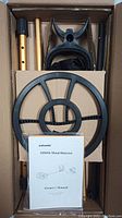 Top view of Nalanda metal detector parts - shafts, coil, armrest, and manual in original packaging.