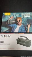 Box of W-King D8 Portable Wireless Speaker showing the model, features, and branding with a man holding the speaker on the front.