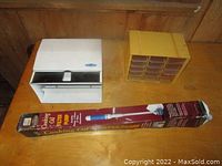 Cooking Oil Filter Pump box with white paper towel dispenser and yellow hardware organizer on a wooden table.