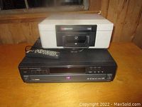 Sentry 1100 safe box placed on top of Hitachi DVD player with remote beside it on wooden surface