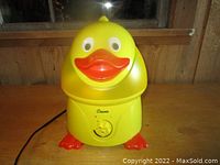 Front view of the yellow plastic duck-shaped humidifier with dial and power cord visible.