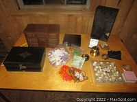 Full view of the assortment on wooden table showing jewelry boxes and jewelry pieces.