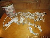 Overview of power bar and multiple corded clip-in light strings with clips and incandescent bulbs spread out on wooden surface.