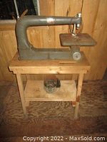 Full view of vintage scroll saw mounted on a wooden stand showing the motor under the table