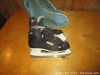Side view of Bauer Charger ice skate with white blade and part of carrying bag visible.