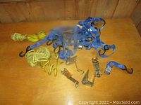 Blue straps, yellow ropes, and small ratchets laid out on wooden surface.