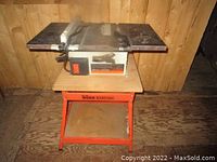 Front view of Black & Decker table saw on orange metal stand inside wooden shed.