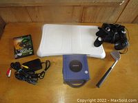 Full view of Nintendo GameCube console, Wii Fit balance board, golf game, golf club controller and cables on wooden surface.