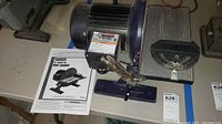 Full view of Central Machinery 10 inch disc sander with owner's manual placed next to it.