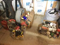 Wide shot showing assortment of automotive fluids including two Mobil 1 synthetic motor oil bottles, oil change pan, various automotive sprays, and parts container.