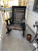 Wooden slat rocking chair on a porch, showing front and side angles