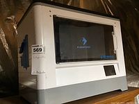 Front view of the white Flashforge Dreamer 3D printer showing the enclosed build area with clear door and touchscreen below.