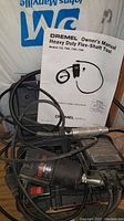 Flex shaft tool with its owner's manual and power cord, showing the flexible shaft attachment.