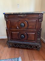 Full front view of ornate wooden dresser with two drawers and circular carved drawer pulls. Marble top visible, wood has a polished dark finish with carved accents.