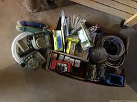 Top-down view of a box containing various electrical items including timers, wall plates, switches, wiring, and junction boxes.