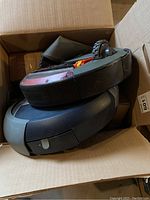 Two black/gray iRobot Roomba 500 series vacuum cleaners placed inside an open cardboard box.