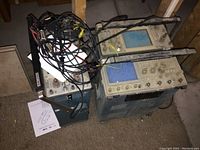 Two oscilloscopes side by side on floor with cables