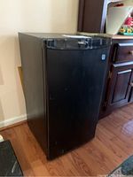 Front side view of the black mini fridge showing its compact size and glossy finish.