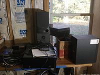 Overall lot with Aiwa speakers, Harman Kardon subwoofer, Yamaha AV receiver on a table in unfinished room.