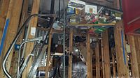 Wide shot of table filled with various boxes of fasteners, tools, level, and saws in basement.