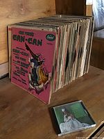Side view of a stack of vinyl records showing album covers including 'Can-Can' soundtrack
