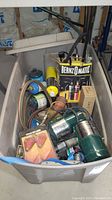 Long view of plastic tub filled with assorted welding tanks, Bernzomatic boxes, wires and tools.