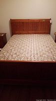 Full view of the wooden bed frame with mattress on top in a bedroom setting.