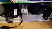 Wide view of shelf holding camera cases and accessories showing multiple items in lot