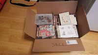 Cardboard box open showing several plastic cases containing rubber stamps for crafting and scrapbooking