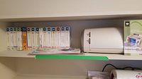 Photo showing 13 Cricut cartridges with colorful labels and titles, next to the white Cricut personal electronic cutting machine.