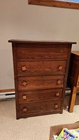 Front view of vintage wooden dresser showing four drawers with square wooden knobs.