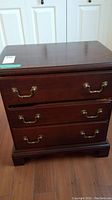 Front view of nightstand showing full unit with three drawers and brass-tone bail handles